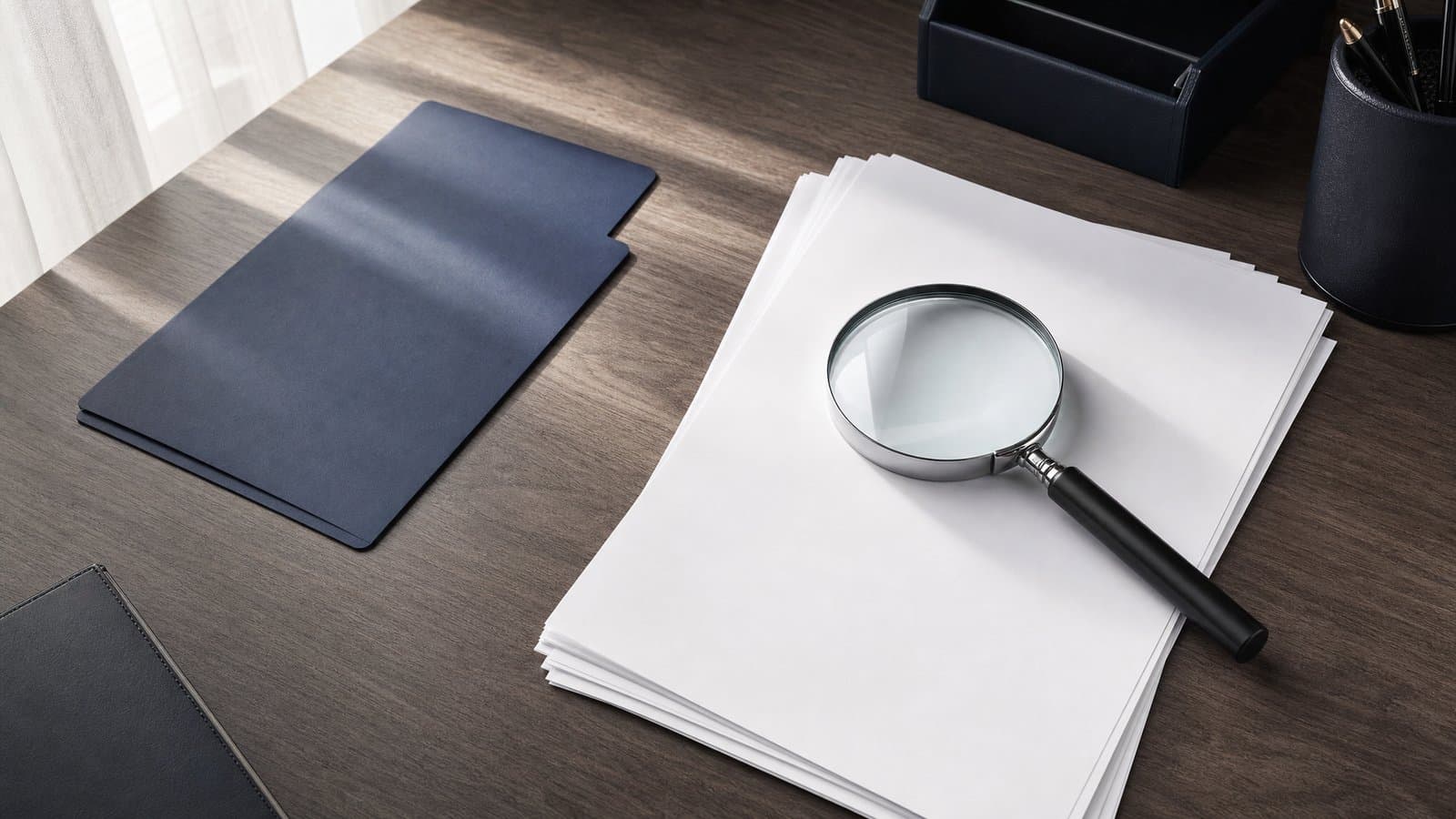 A magnifying glass resting on blank documents — Korean courts can search a debtor's bank accounts and registered property on the creditor's application